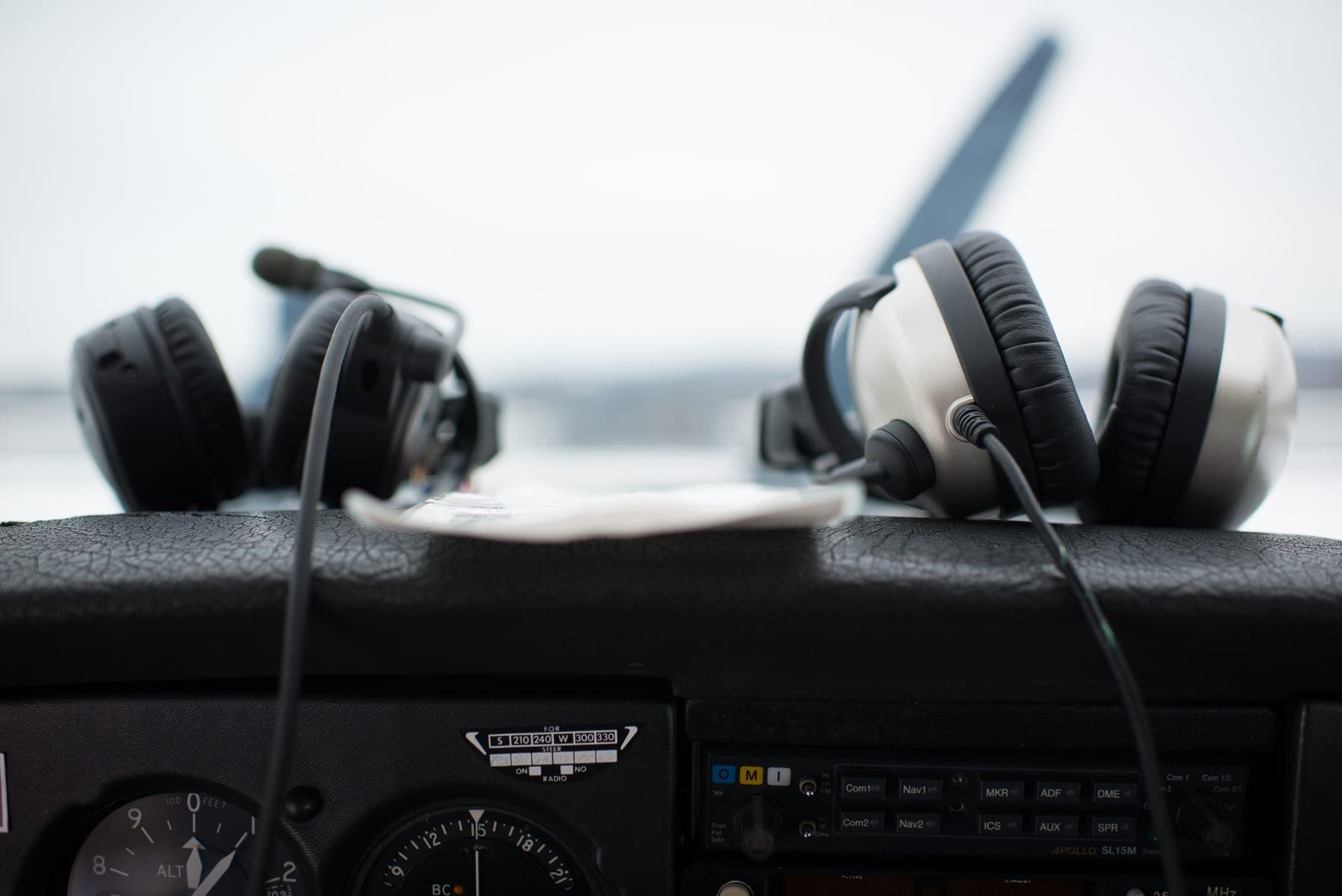 Two headsets on the glareshield of a training aircraft, ready for the next lesson.
